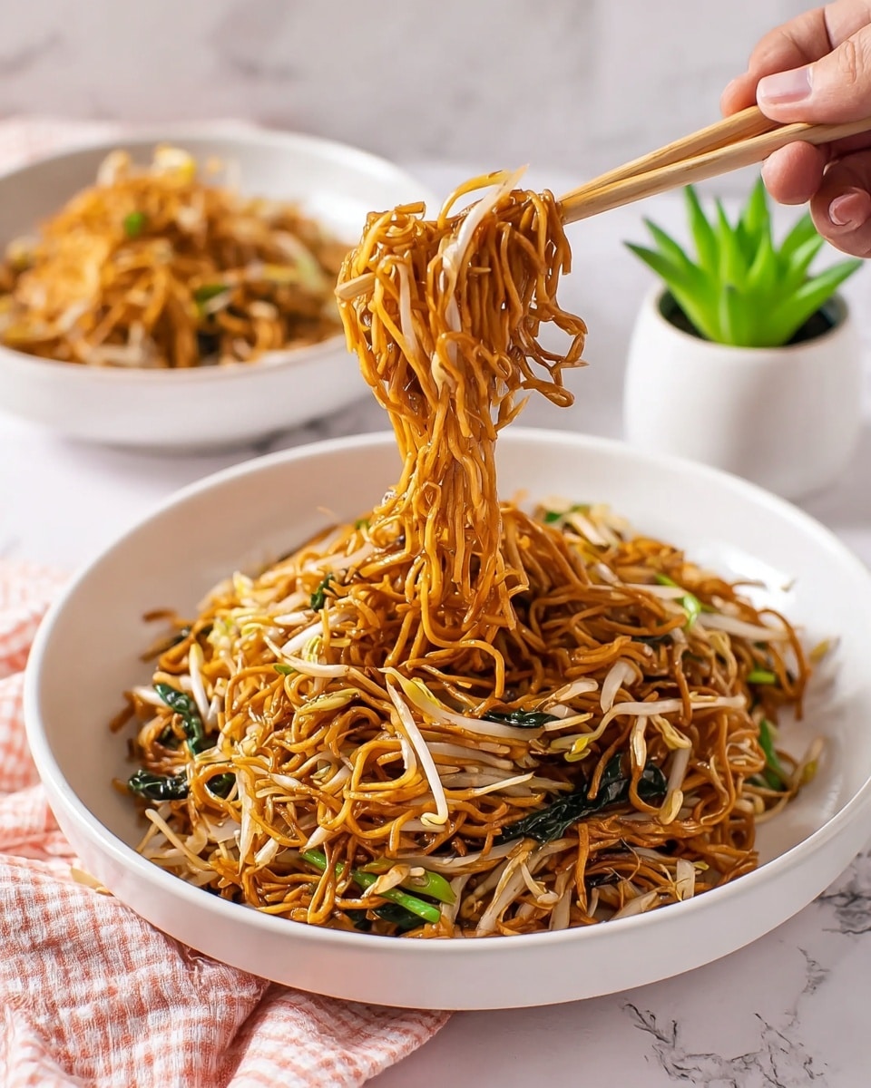 A white round plate filled with a large serving of stir-fried noodles makes the main focus of the image. The noodles are thin and golden brown, mixed with layers of bright green spring onions and translucent light beige bean sprouts, scattered evenly throughout. The dish has a shiny, slightly oily texture, indicating it was cooked with sauce. The plate is on a white marbled surface, near light pink chopsticks and a small green potted plant on the side. In the background, there is another white plate with more noodles and a light pink glass with ice. A pink and white checkered cloth is placed under the plate on the bottom left corner. Photo taken with an iphone --ar 4:5 --v 7