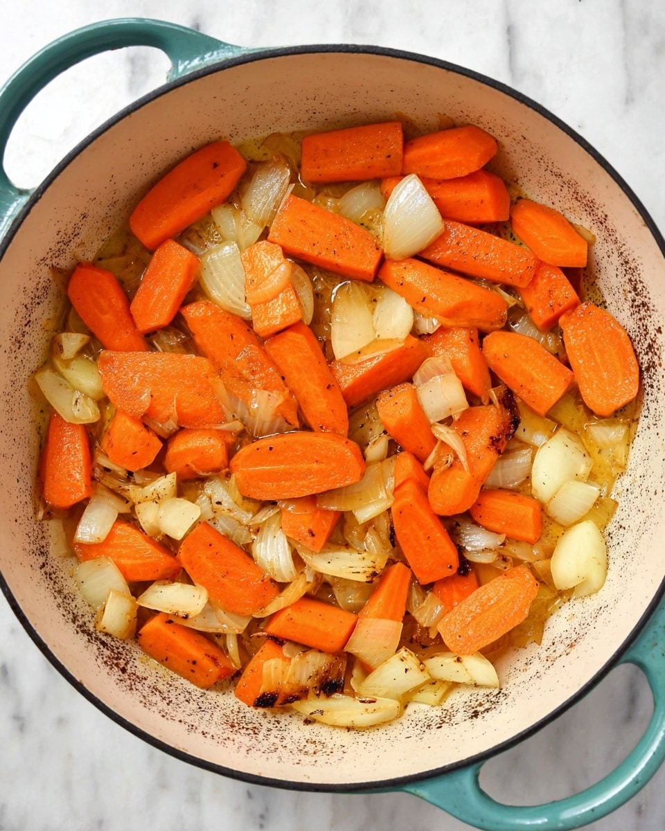 A top-down view of a white cast iron pot with a teal handle, filled with two main layers: large chunks of bright orange carrot pieces and pale yellow chopped onions, both slightly glistening with oil and lightly cooked, showing some brown spots in the pot where vegetables have started to caramelize. The carrot slices are oval-shaped, scattered evenly among the irregular onion pieces, creating a textured and colorful mix. The pot sits on a white marbled surface photo taken with an iphone --ar 4:5 --v 7