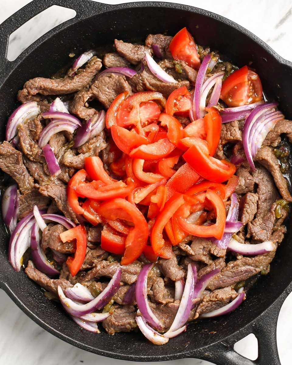 A close-up top view of a black cast iron skillet filled with three main layers: the bottom layer is cooked, thinly sliced brown beef strips mixed with thin slices of purple and white onion, creating a textured, slightly glossy base; on top, there is a pile of bright red tomato wedges and strips that add a fresh and juicy contrast in the center of the pan. The skillet rests on a white marbled surface. photo taken with an iphone --ar 4:5 --v 7