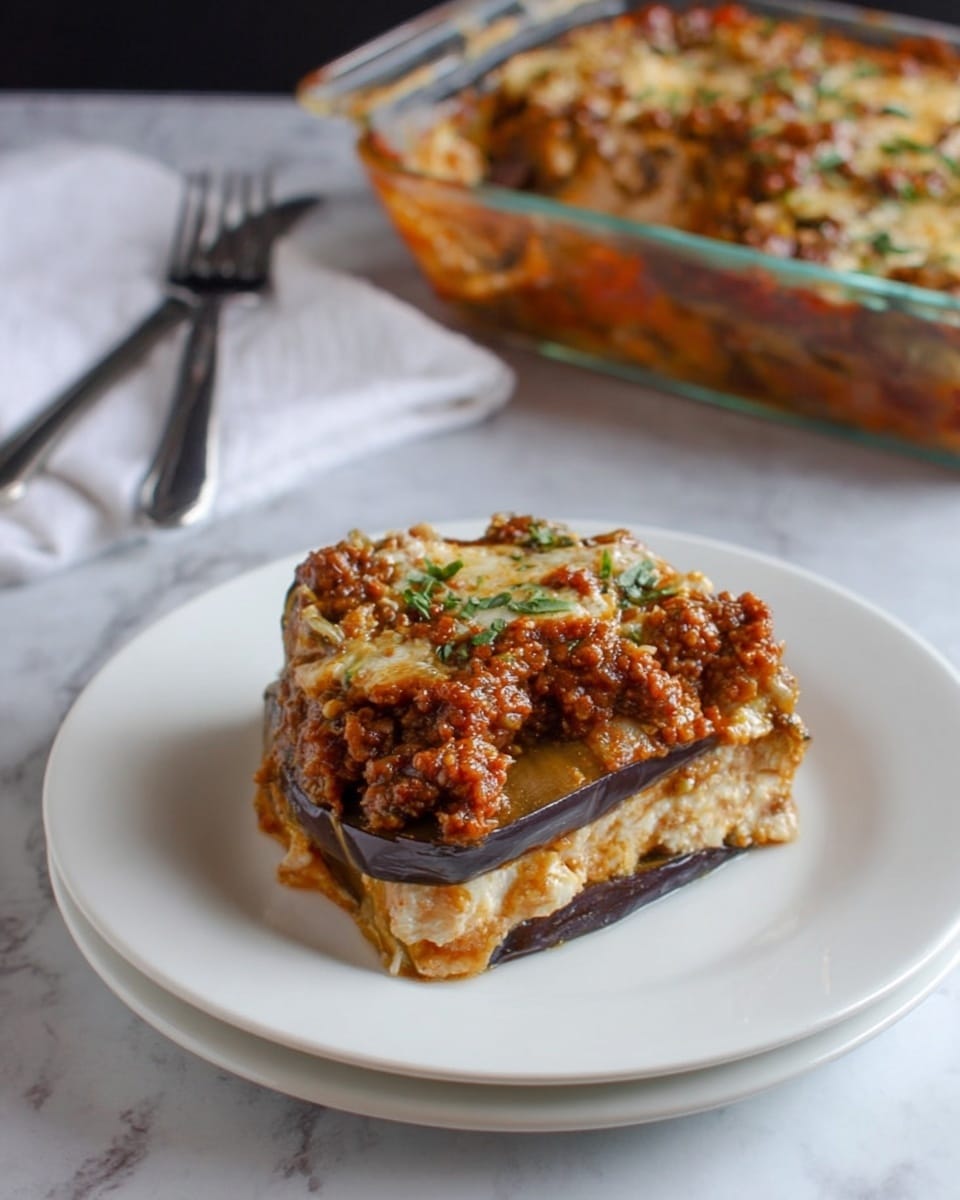 A white plate holds a layered dish with at least four visible layers, starting with dark purple slices of eggplant at the bottom, followed by alternating layers of creamy beige cheese mixed with a light brown sauce. The top layer is a chunky, reddish-brown meat sauce with some green herb leaves scattered across it. The dish sits on a white marbled surface, with a glass baking dish of the same meal in the background. Two forks rest on a white napkin nearby. photo taken with an iphone --ar 4:5 --v 7